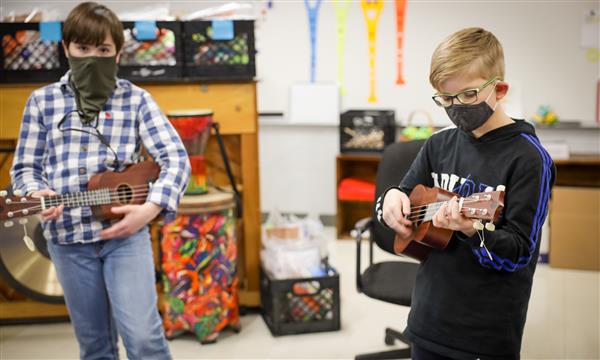two boys play ukulele